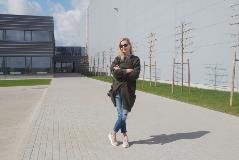 Architect Ignė Grigaliūnaitė from architects Kita kryptis stands in the yard in front of the building she designed. 